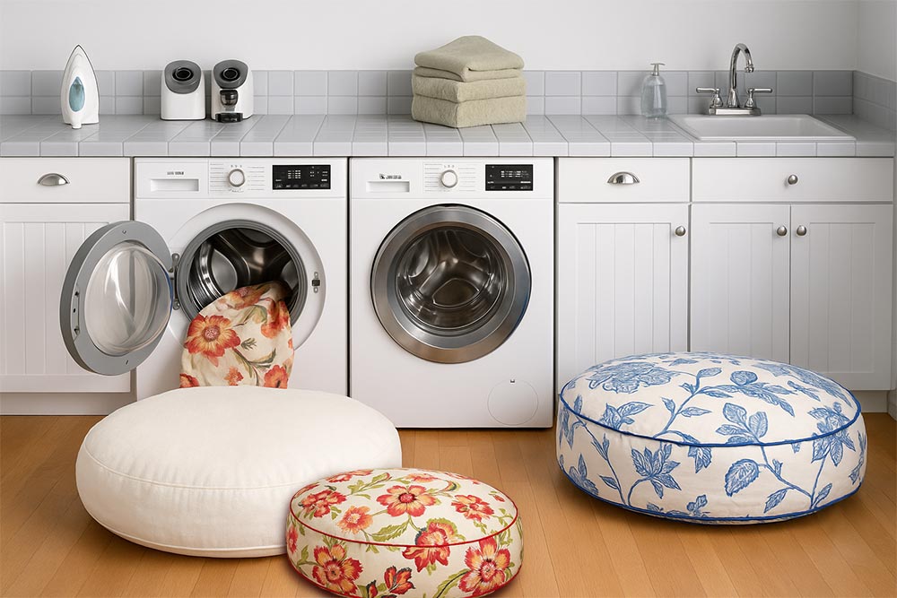 Laundry room with three round dog beds. One bed's cover is partially in the front load washing machine.